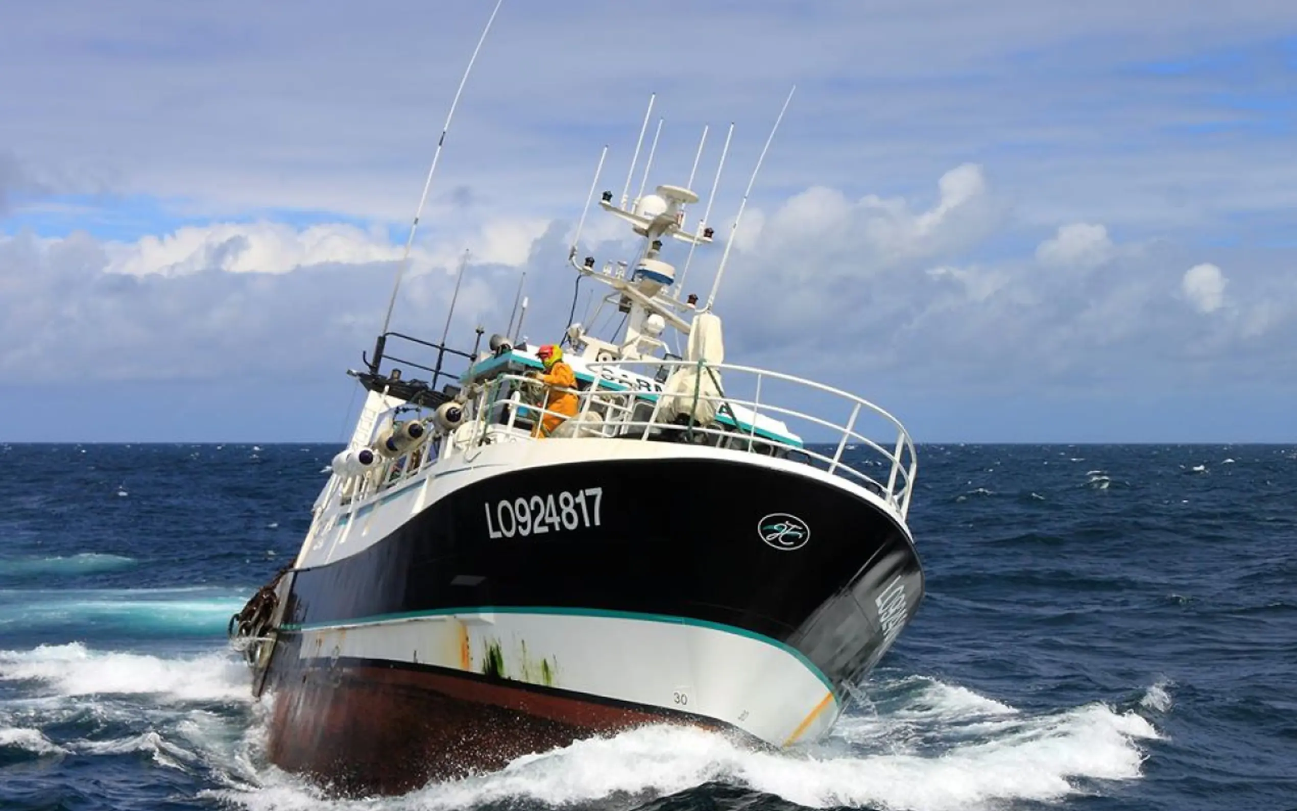 Chalutier de l'armement APAK voguant sur une mer bleue, coque noire et liseré vert